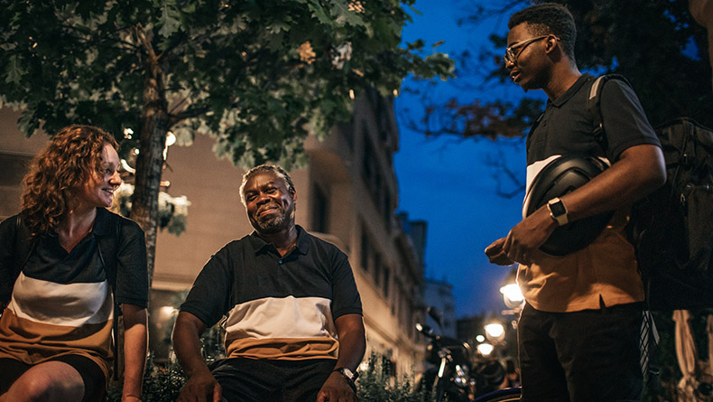 Three delivery workers are chatting on a break from work.