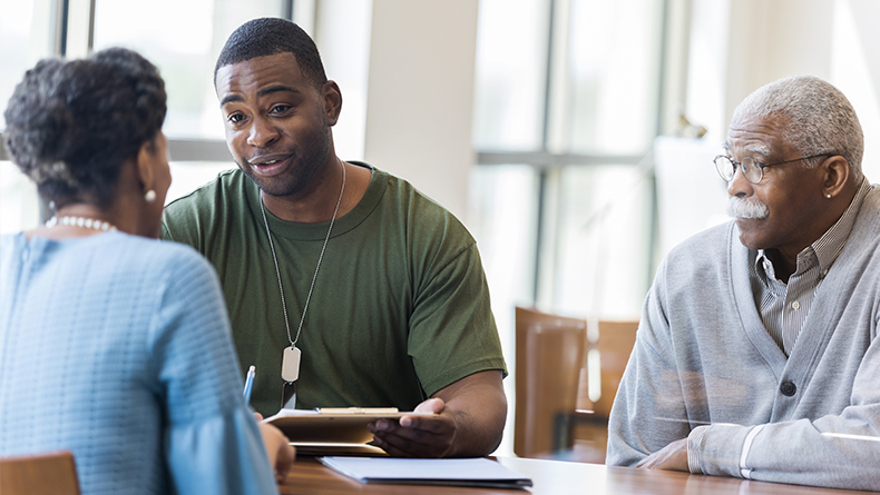 Three people sit around a table looking over paperwork.