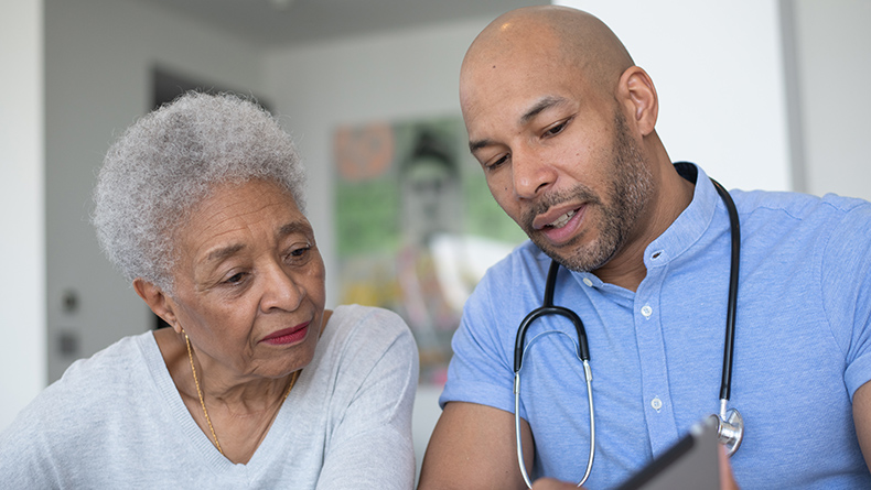 Male physician and female patient look at a tablet 