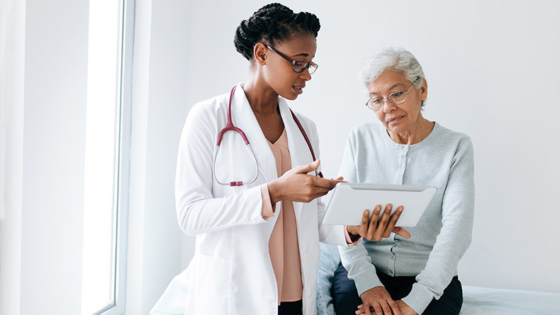 Black female doctor showing digital tablet to senior patient