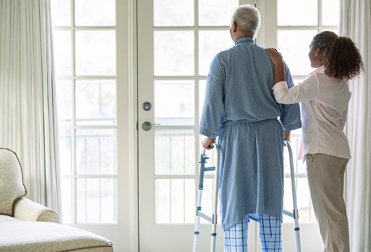 African American woman helping Senior man use walker