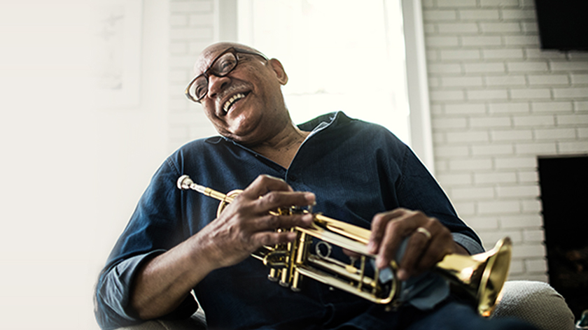 A man smiling as he holds a trumpet