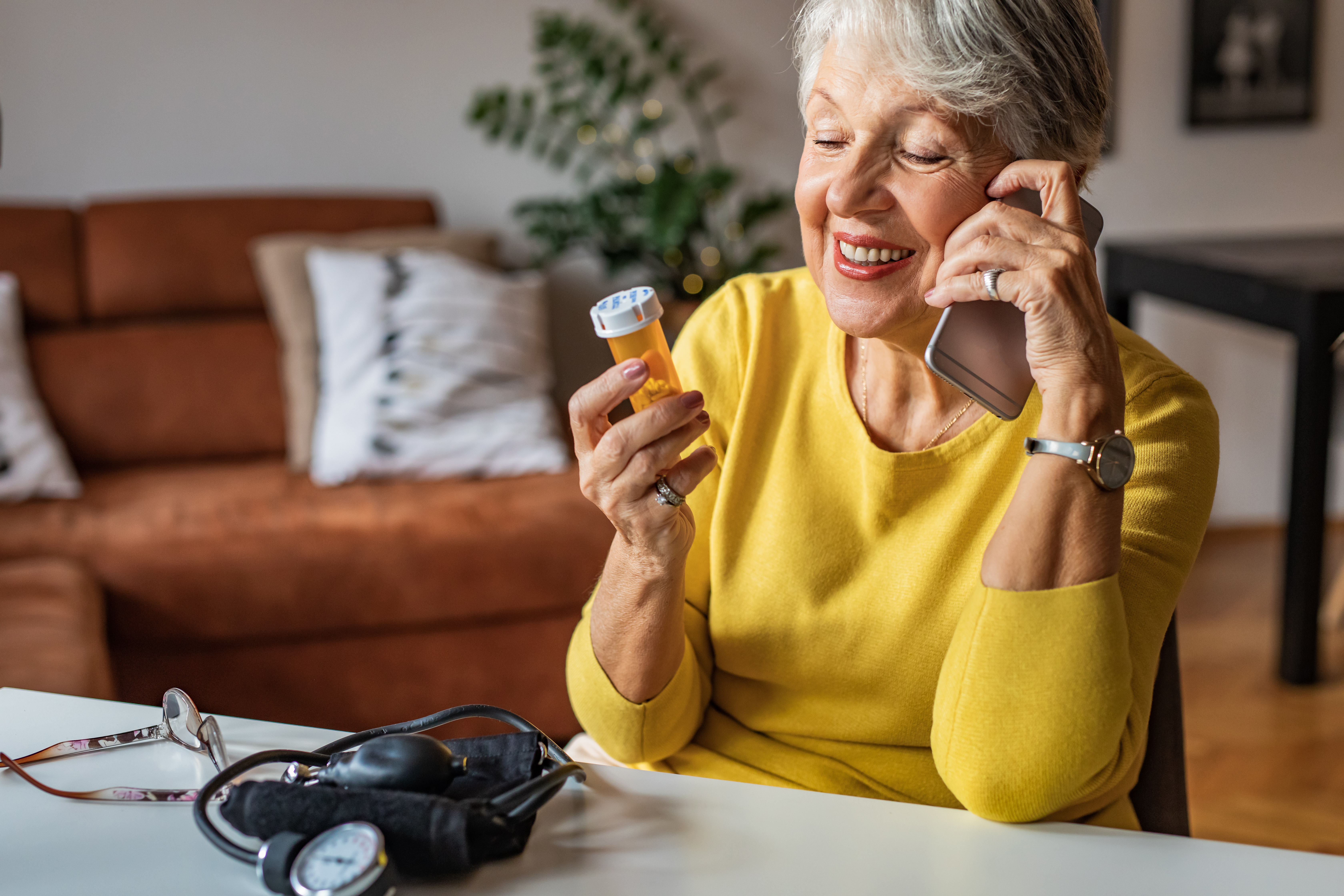 Senior woman talking with a doctor on the phone and holding a pill bottle