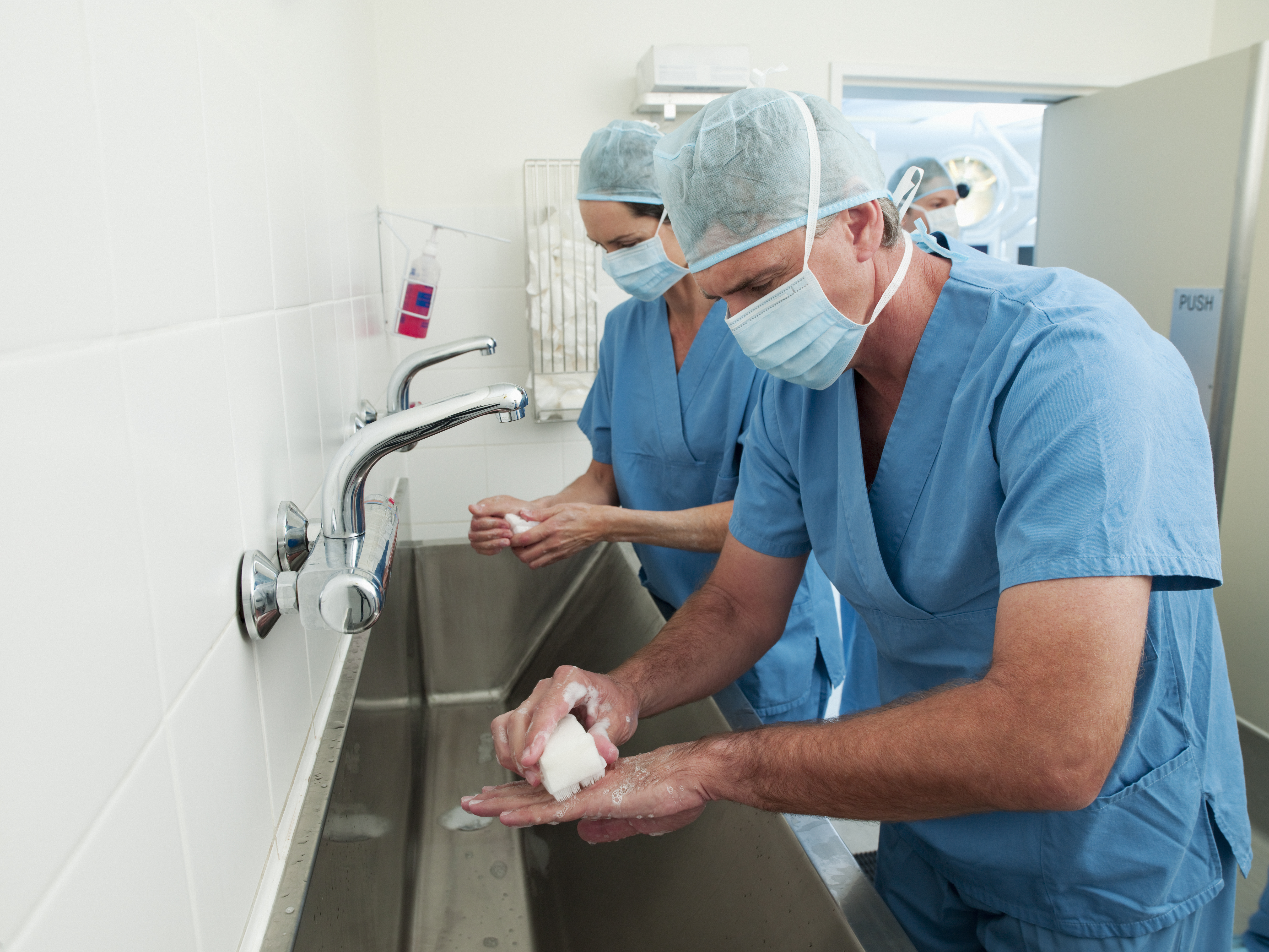 Surgeons in scrubs washing hands at sink